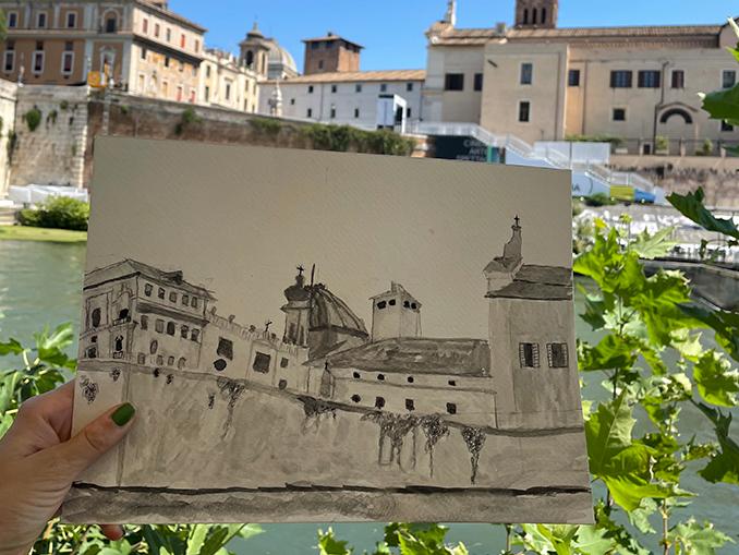 study abroad student holding up a finished sketch of old buildings along Italy's Tiber river