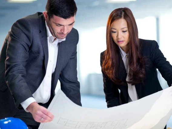 Businessman and woman examining blueprints 