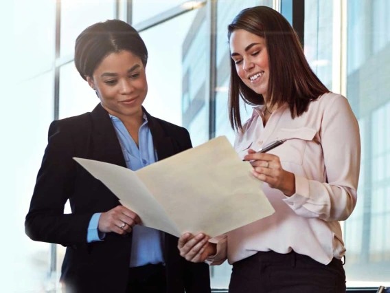 Two professional women discussing paperwork