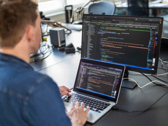 man looking at laptop screen with code