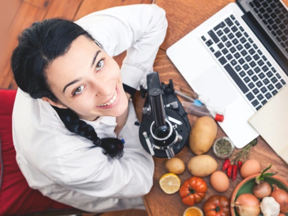 Woman with laptop, microscope, and produce