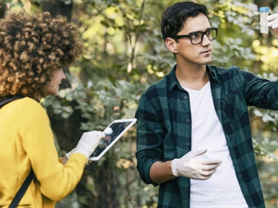 students in the forest looking at water sample