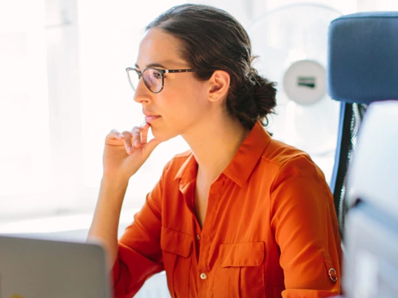 Woman thoughtfully looking at computer screen