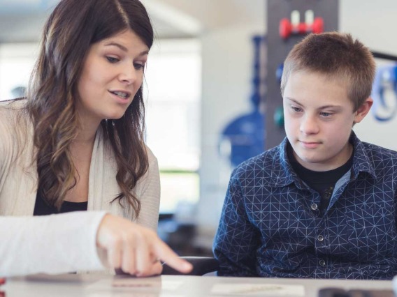 Therapist pointing to cards with boy watching