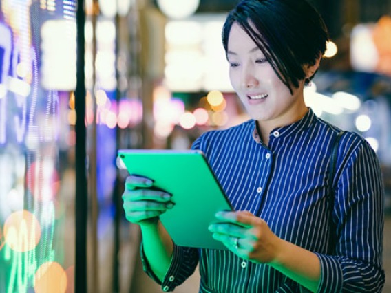 Women looking at her tablet near a stock market sign