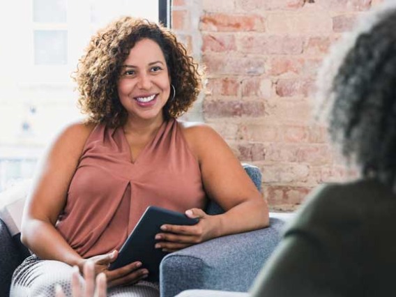 woman talking to another woman with tablet in her hands