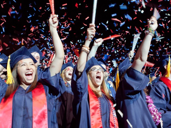 graduate students in caps and gowns celebrating