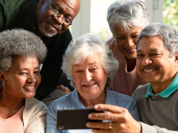 group of senior adults laughing at phone video