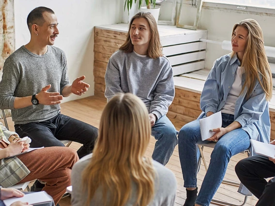 addiction recovery group sitting in circle sharing experiences 