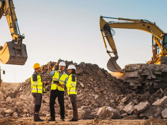 Mine engineers standing in front of diesel excavators at a worksite 