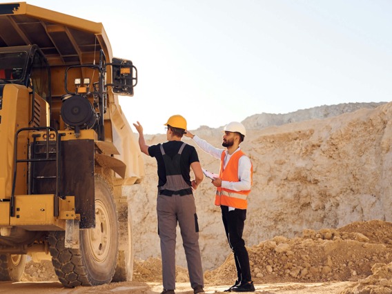 Mine workers discussing safety protocol next to a large machine