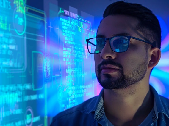 A focused data scientist wearing glasses looks at a glowing display of code and graphs, surrounded by vibrant blue and purple lights, conveying a high-tech and futuristic atmosphere.