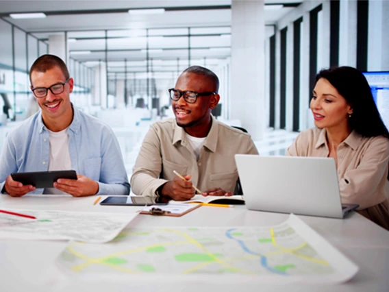 three people at a conference table looking at maps and computers