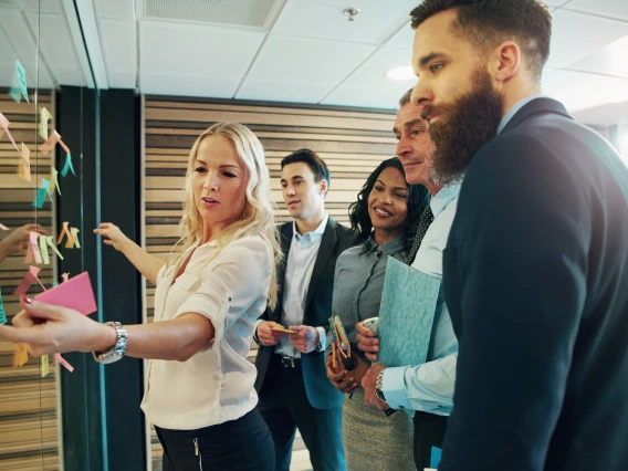 A group of professionals discussing notes on a board. 