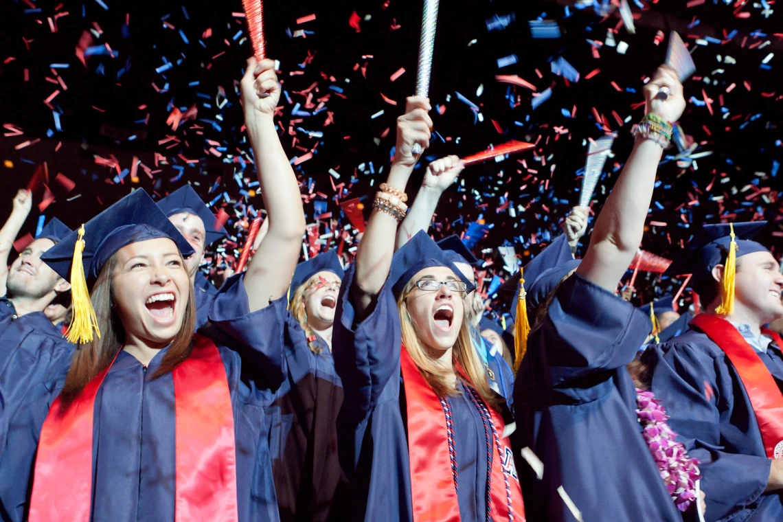 graduate students in caps and gowns celebrating