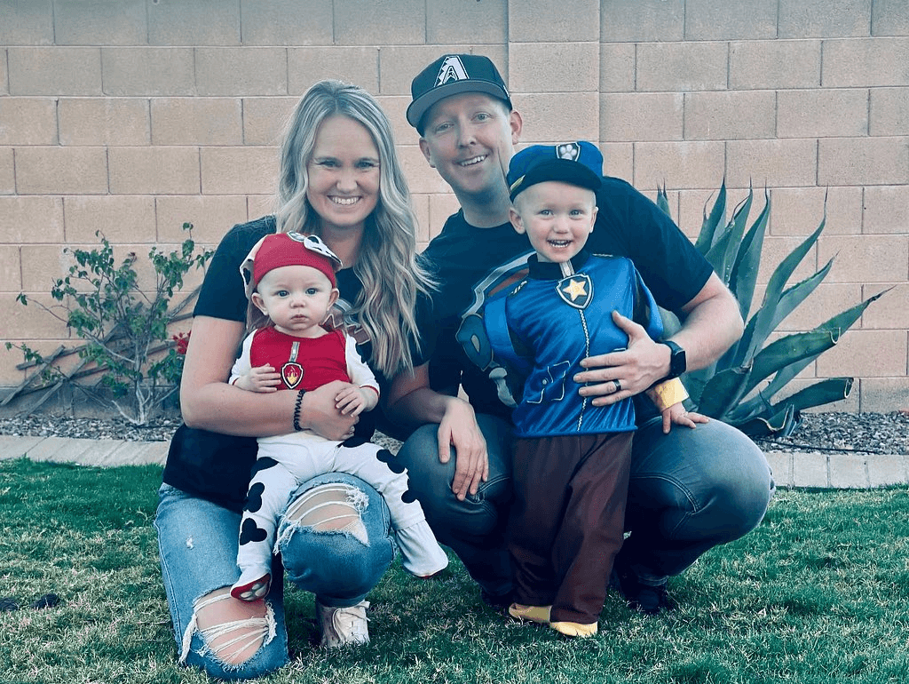 two adults each holding a small child with Halloween costumes on