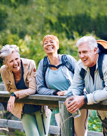 three happy older aged adults hiking and laughing 