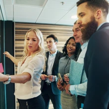 A group of professionals discussing notes on a board. 