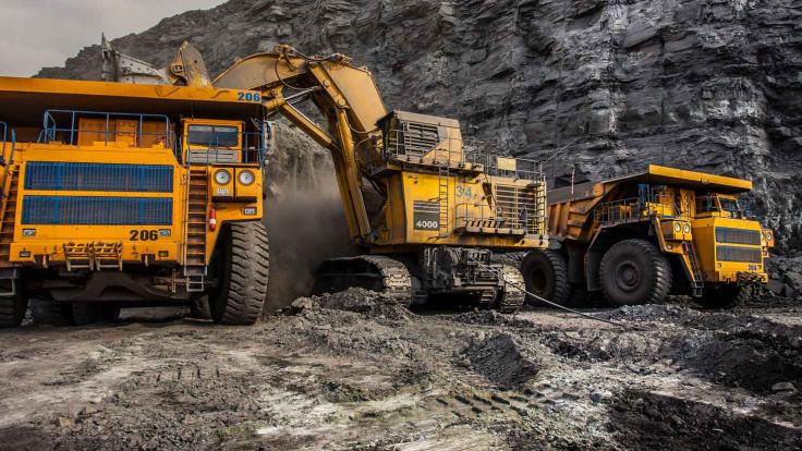 Yellow mining trucks at digging and loading earth