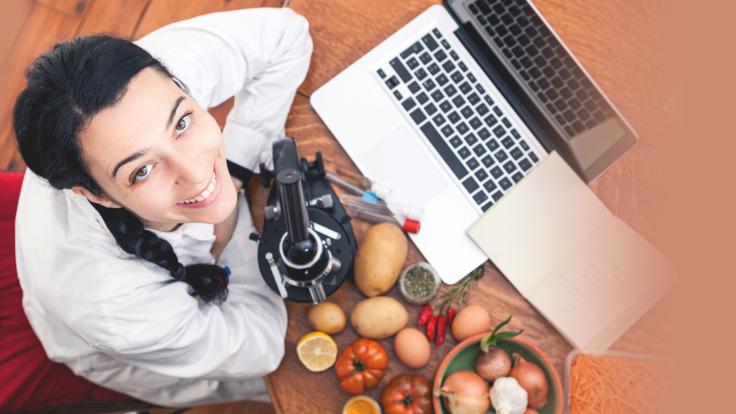 Woman with laptop, microscope, and produce