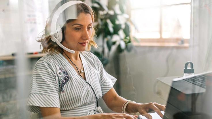 Woman working at a laptop with headphones on