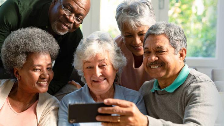 group of senior adults laughing at phone video