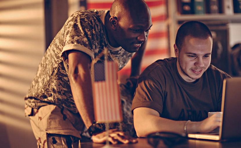 two military men looking at a laptop