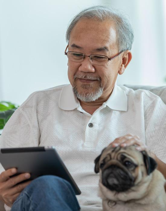 Older man reading from a tablet with a dog
